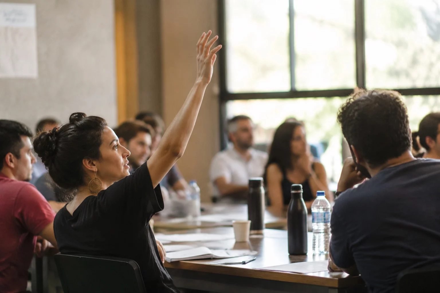 Estudante levantando a mão em uma mesa de seminário coberta de anotações